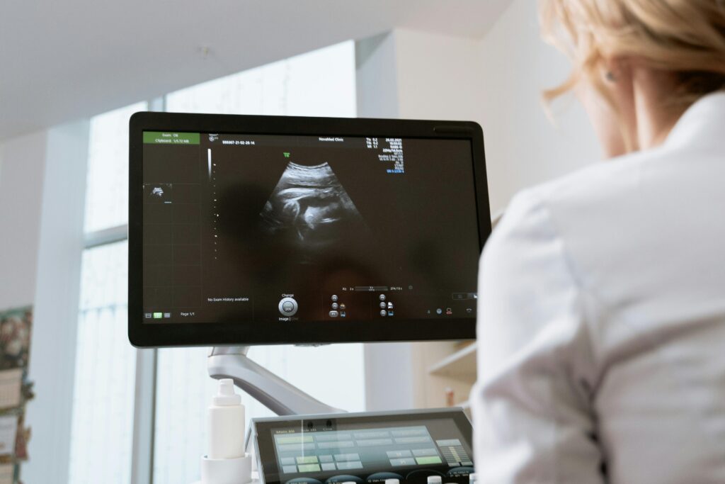 Healthcare professional viewing ultrasound scan on a monitor during a medical examination.